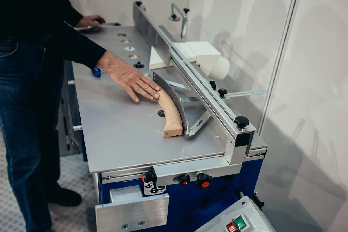 Router table setup in a woodworking workshop, showing fence, bit and feed direction