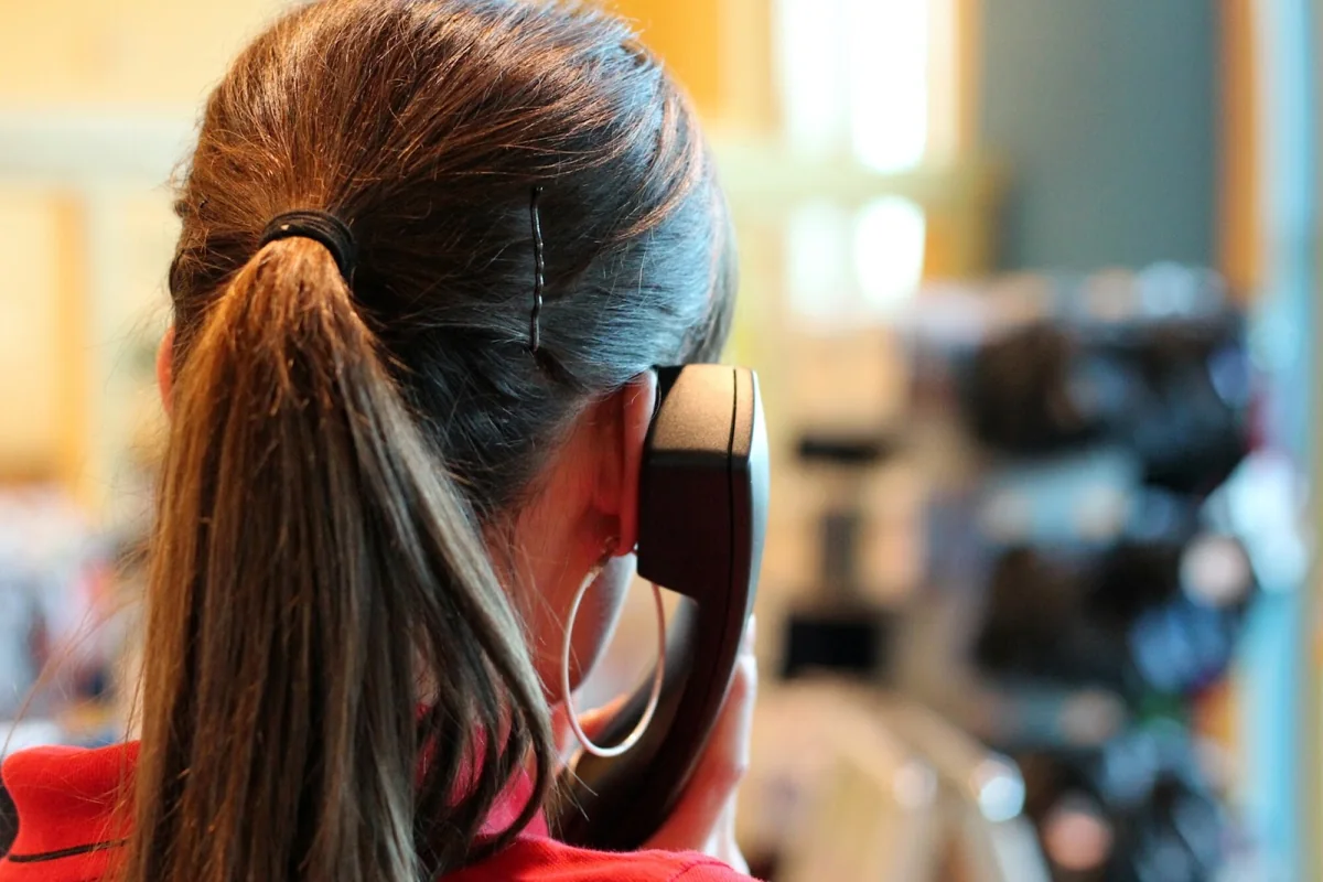 Person holding a telephone receiver at an office desk