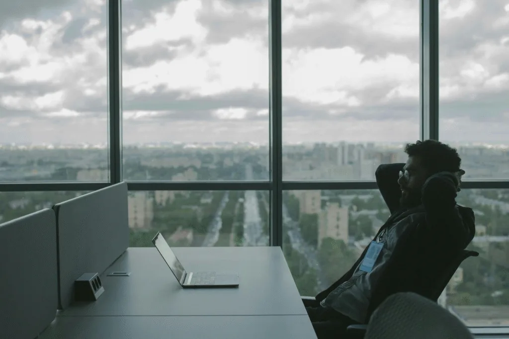 Person using a laptop beside large office windows