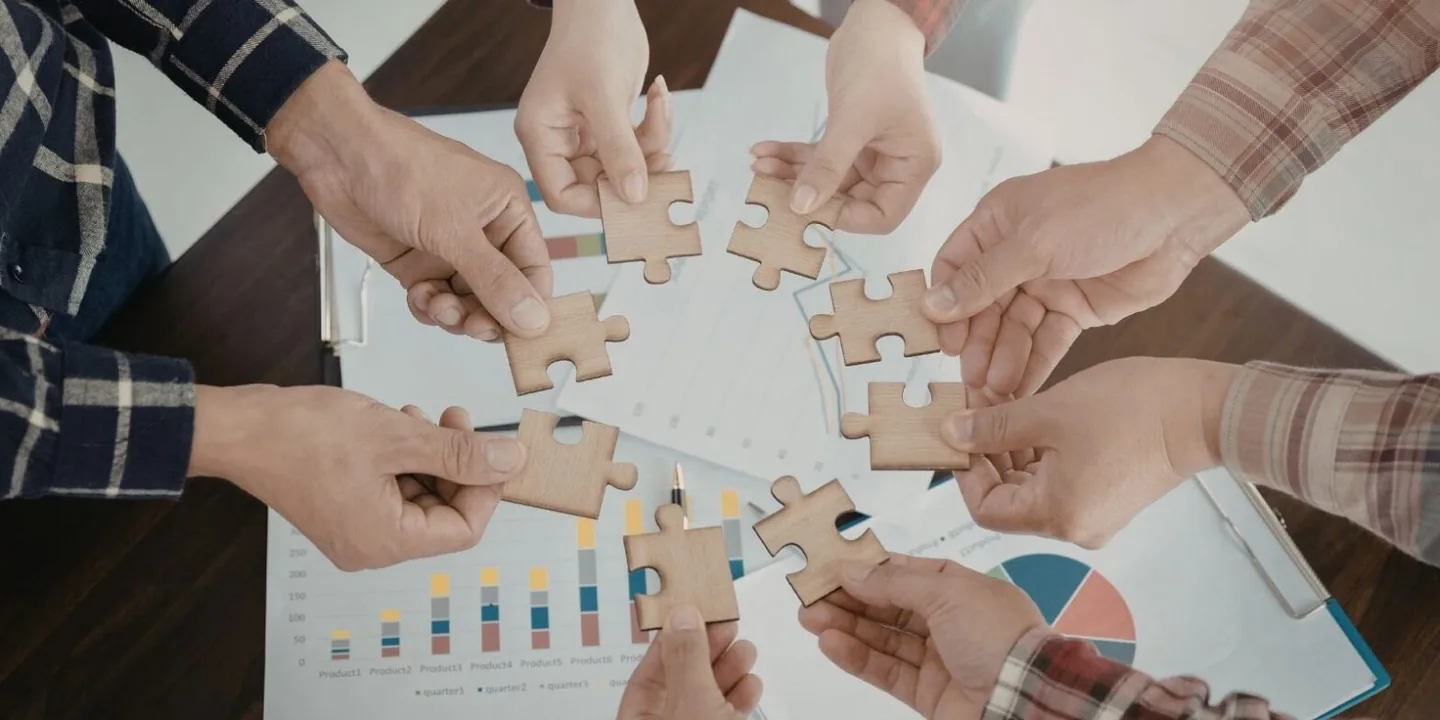 Hands joining puzzle pieces together symbolizing partnership with IT staff augmentation companies